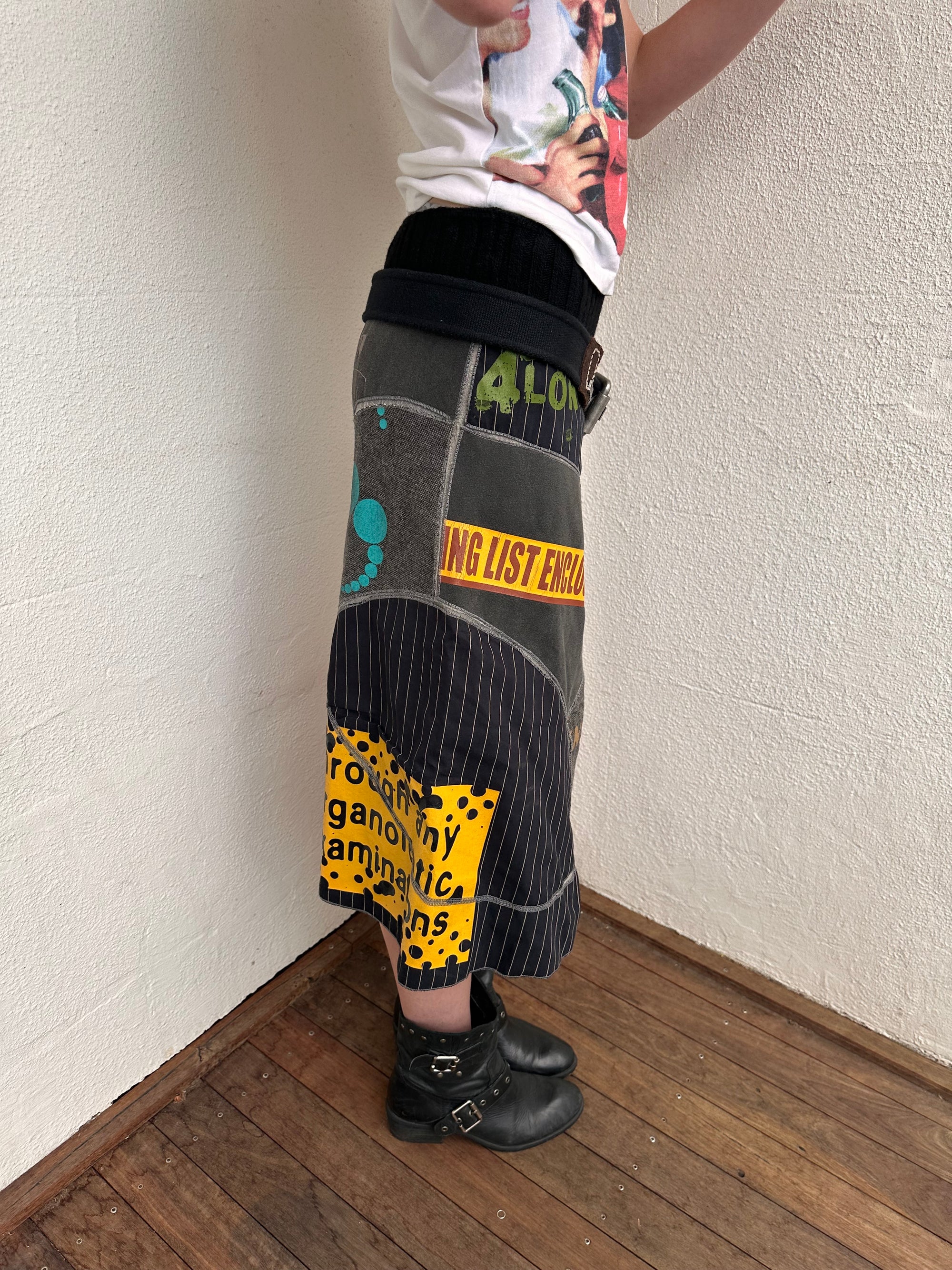 Woman wearing a Y2K 00s grey patchwork midi skirt featuring a bold, multi-coloured print design.