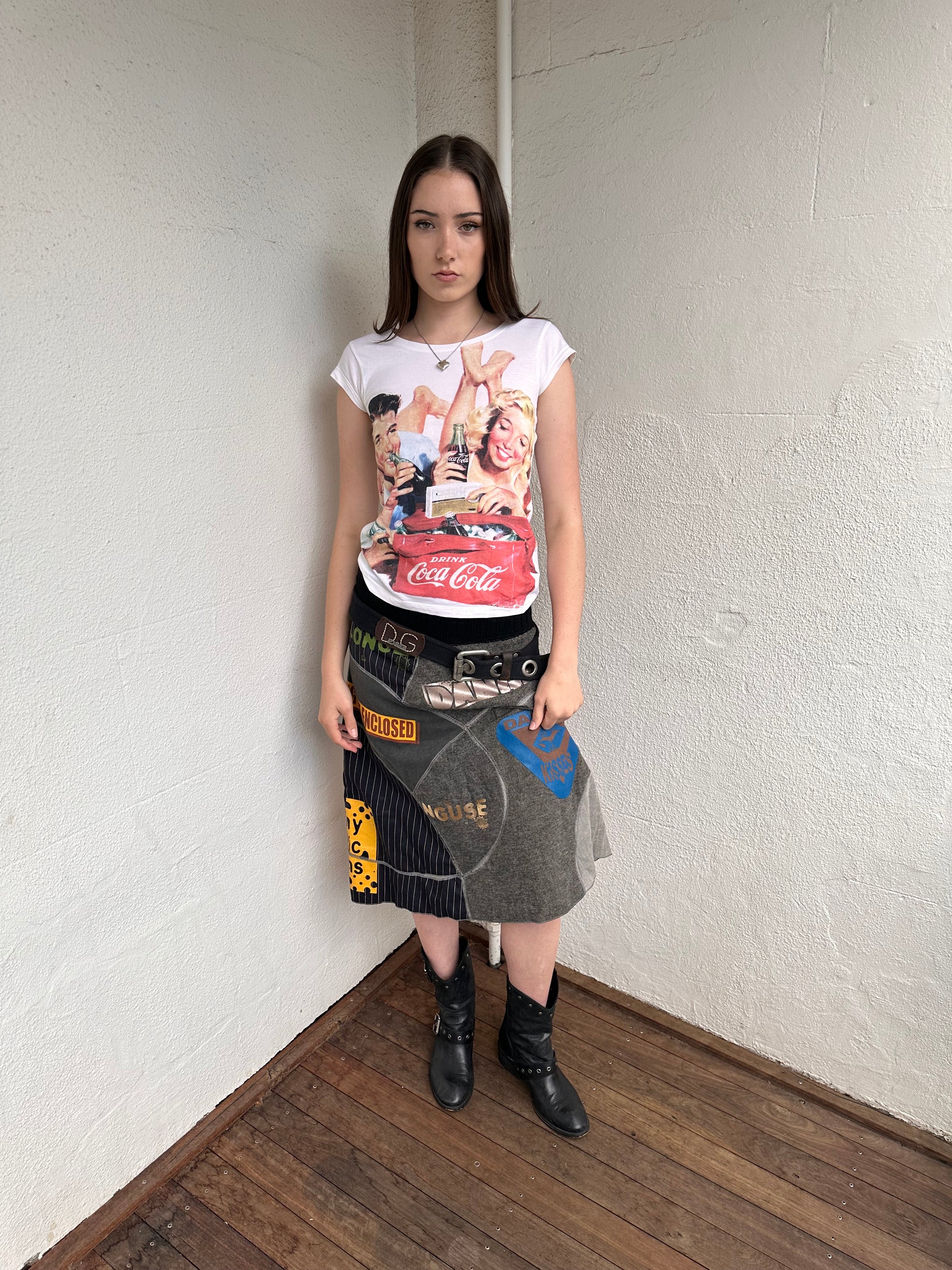 Woman wearing a Y2K 00s grey patchwork midi skirt featuring a bold, multi-coloured print design.
