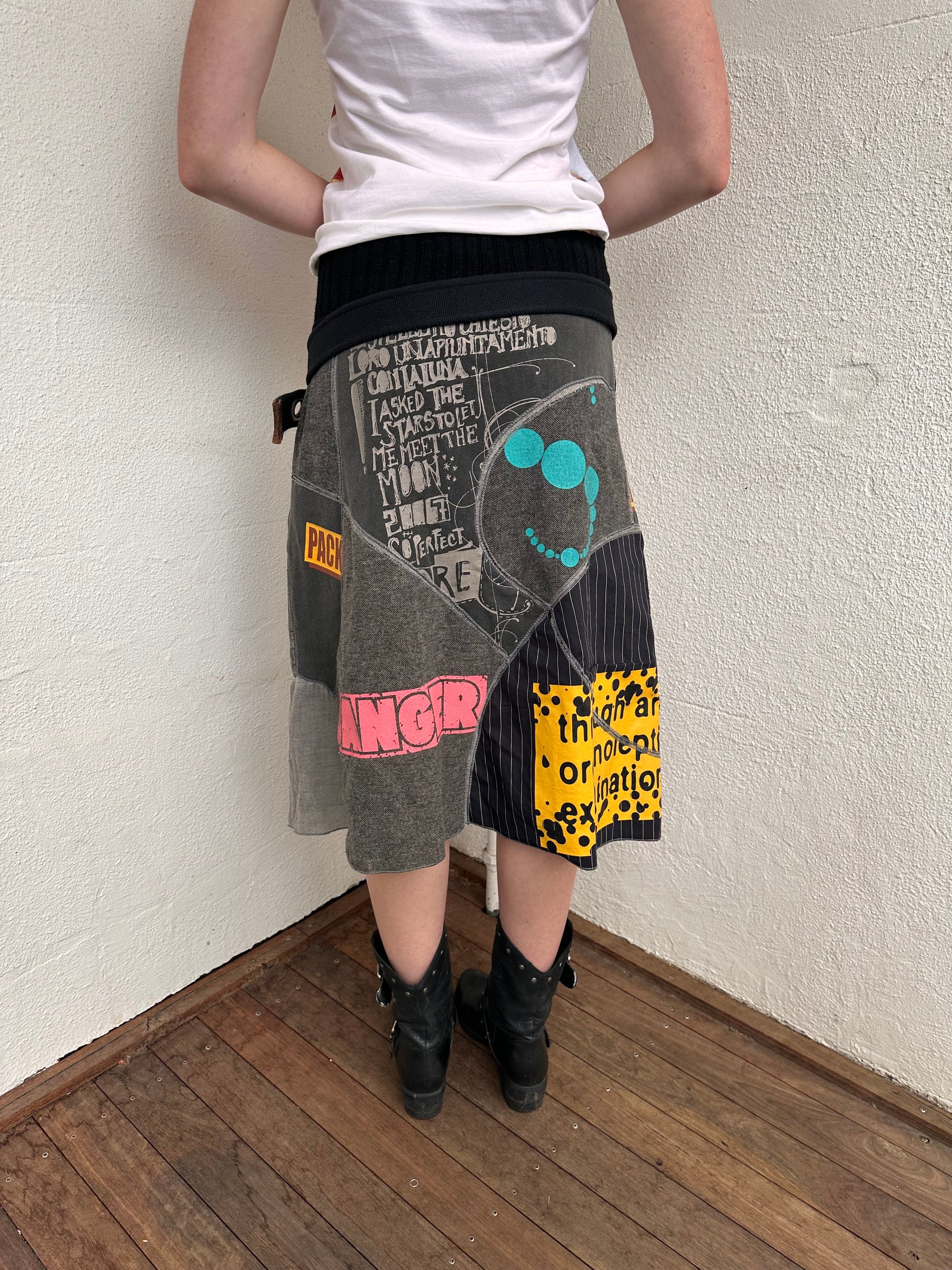 Woman wearing a Y2K 00s grey patchwork midi skirt featuring a bold, multi-coloured print design.