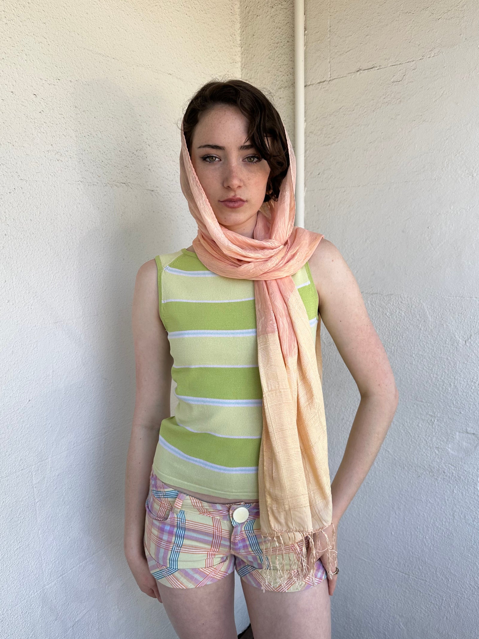 Woman Dressed in Y2K Peach and gold patterned festival scarf featuring a sheer silk-style fabric with a small circular pattern and gold fleck detailing throughout.