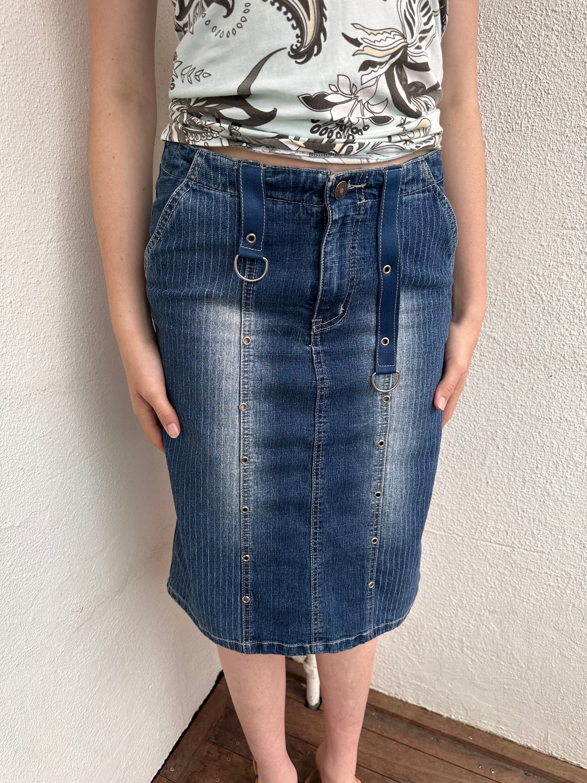 Woman wearing a Y2K 00s Pinstripe denim midi skirt featuring silver D-rings and grommet detailing across the front.