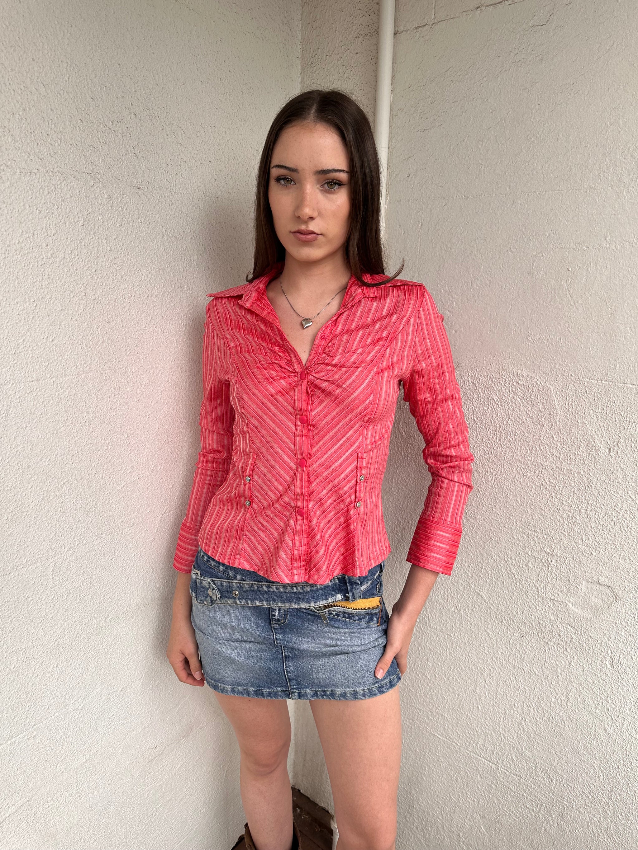 Woman wearing a Y2K 00s Pink pinstripe fitted shirt with a tailored silhouette and with a subtle shimmer to it.