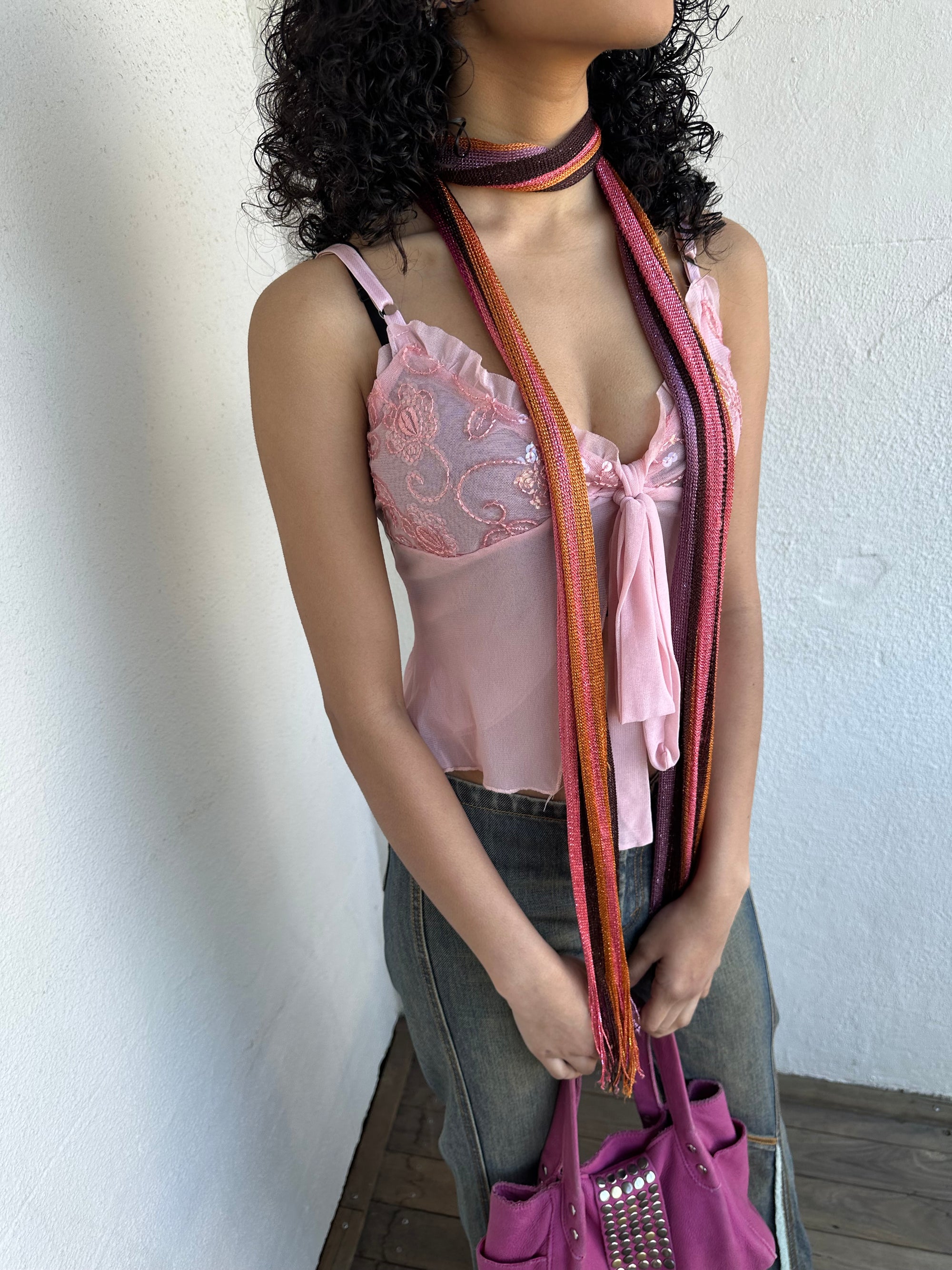 Woman wearing a Y2K 00s Hot pink, orange & lilac stripe shimmer skinny scarf from the 00s.