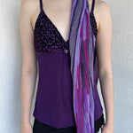 Woman Dressed in Y2K Purple striped festival scarf featuring a striking linear pattern with bold purple tones & flex of silver.