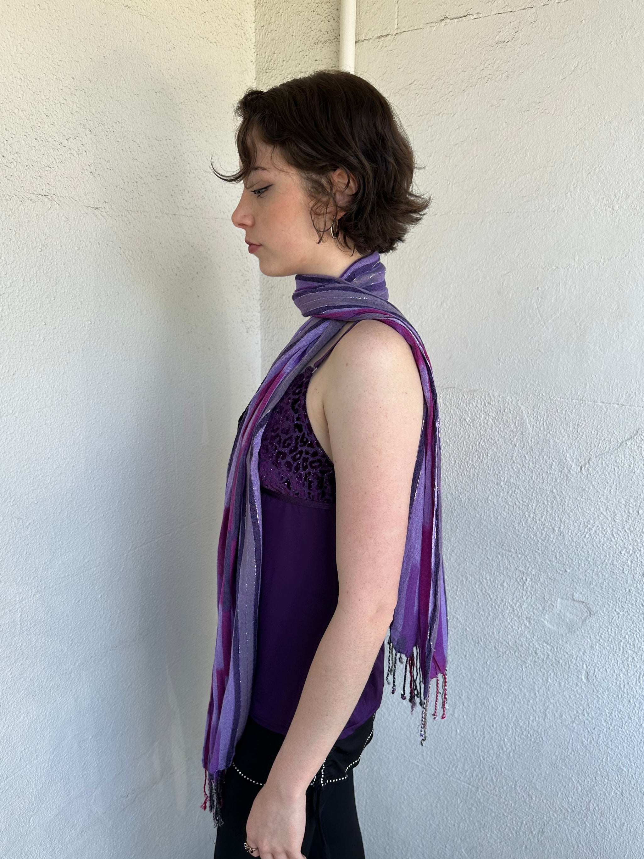 Woman Dressed in Y2K Purple striped festival scarf featuring a striking linear pattern with bold purple tones & flex of silver.