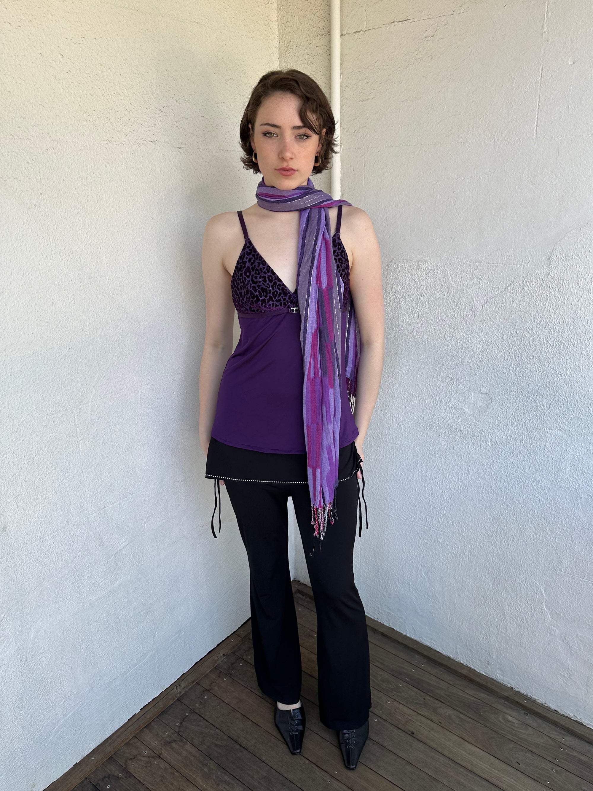 Woman Dressed in Y2K Purple striped festival scarf featuring a striking linear pattern with bold purple tones & flex of silver.