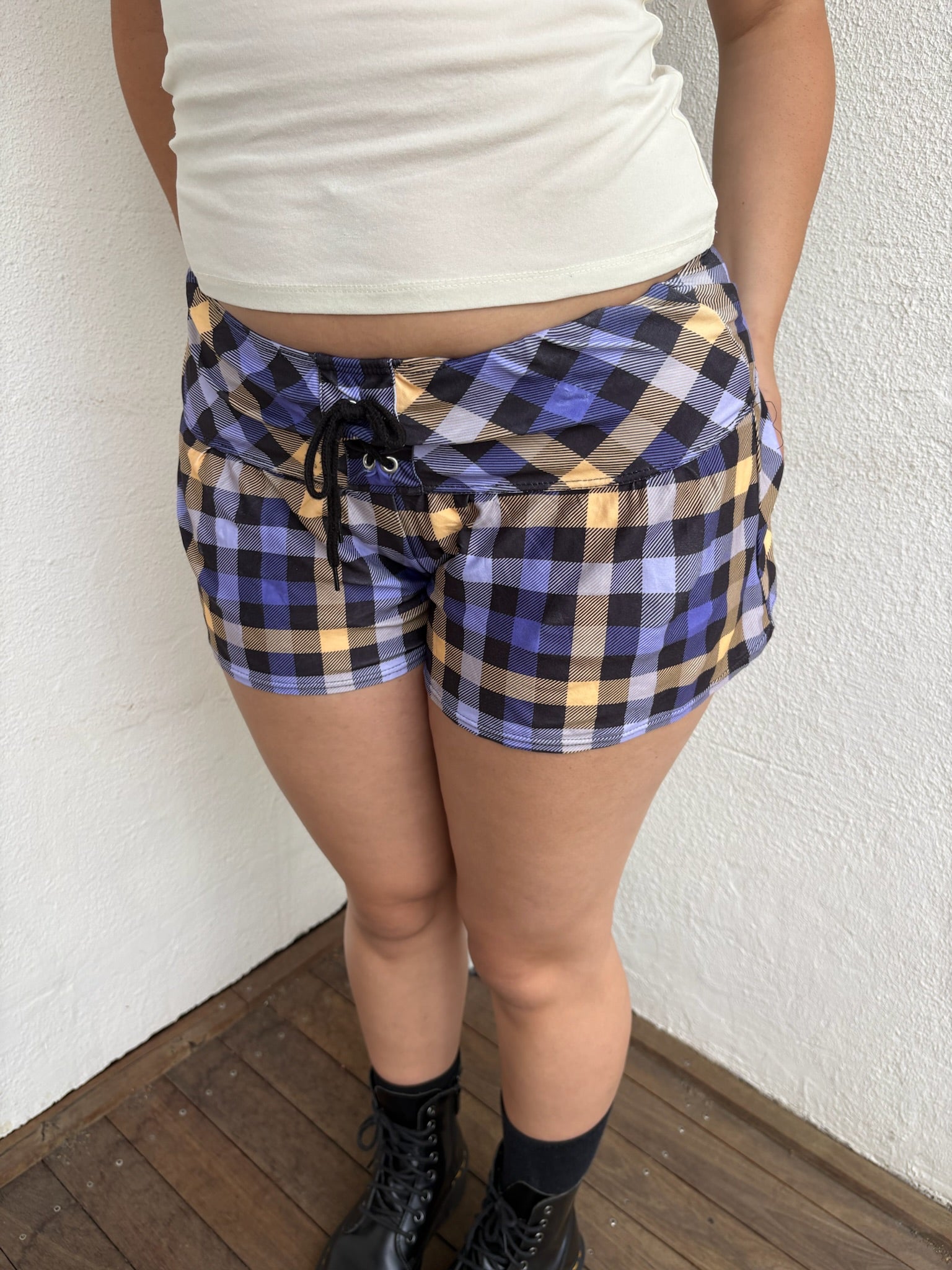 Woman Dressed in Y2K 00s Purple and yellow check booty shorts featuring a vibrant check pattern in purple and yellow tones.