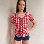 Women wearing a 00s Y2K Red and white checkered blouse with an off-the-shoulder design and chunky buckle straps. 