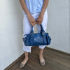 Woman wearing a Y2K 90s Royal blue faux leather shoulder bag with silver hardware and a sleek, structured shape. 