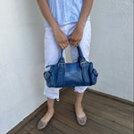 Woman wearing a Y2K 90s Royal blue faux leather shoulder bag with silver hardware and a sleek, structured shape. 
