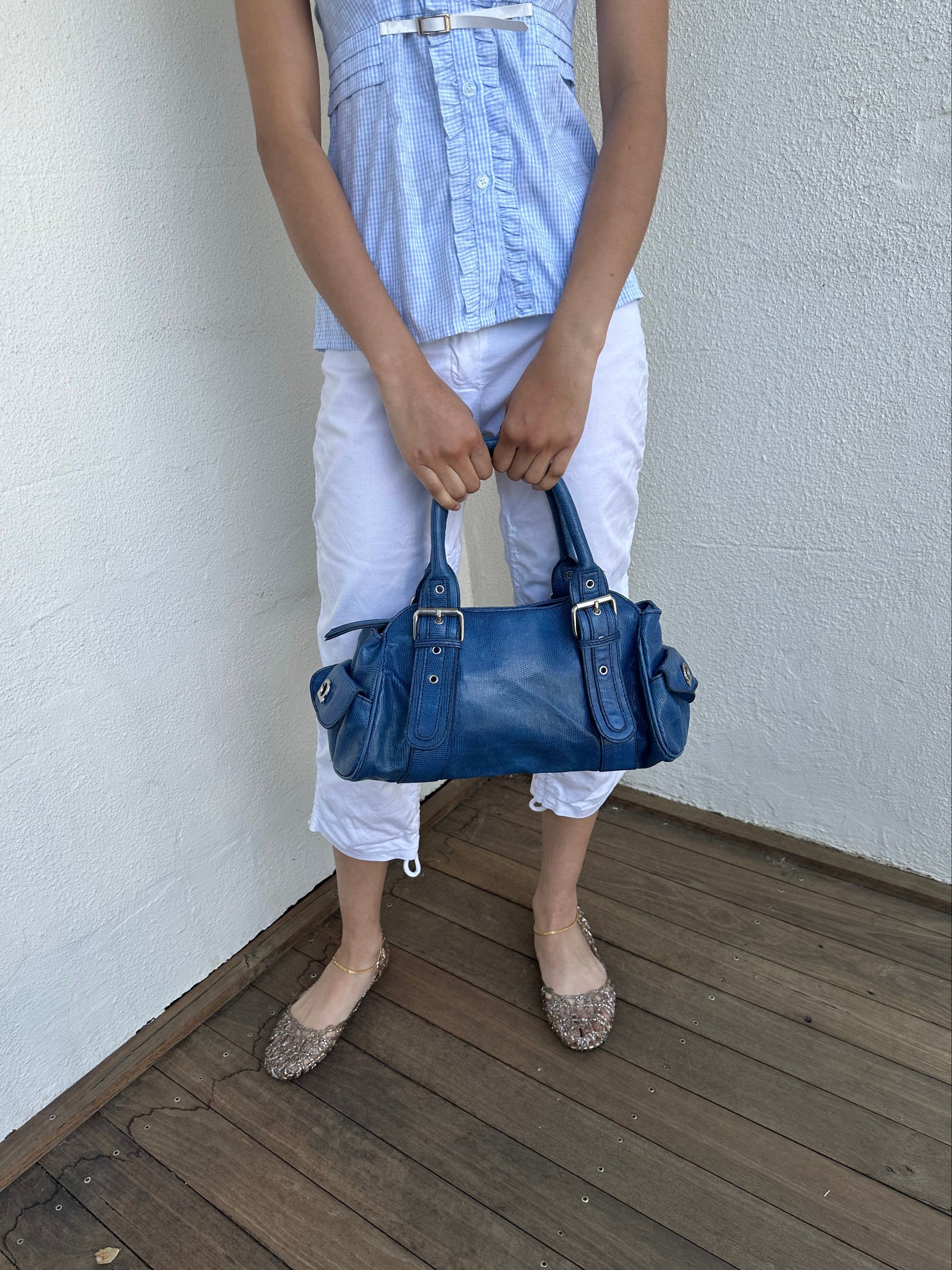 Woman wearing a Y2K 90s Royal blue faux leather shoulder bag with silver hardware and a sleek, structured shape. 