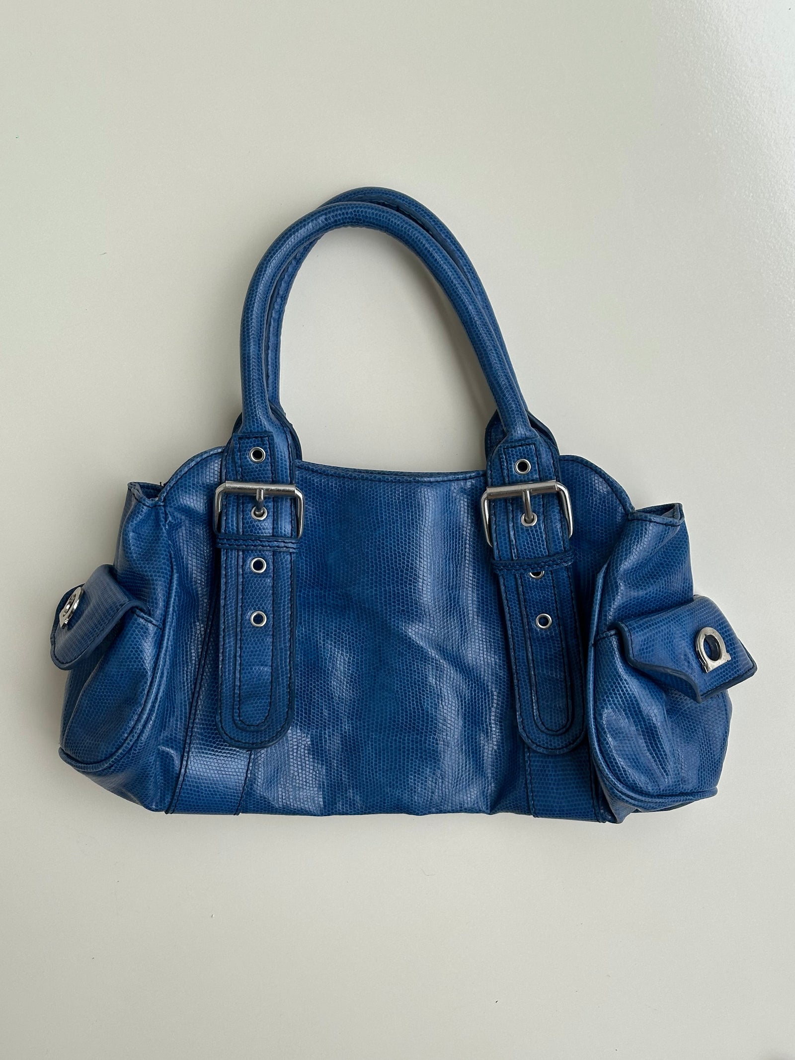 Woman wearing a Y2K 90s Royal blue faux leather shoulder bag with silver hardware and a sleek, structured shape. 