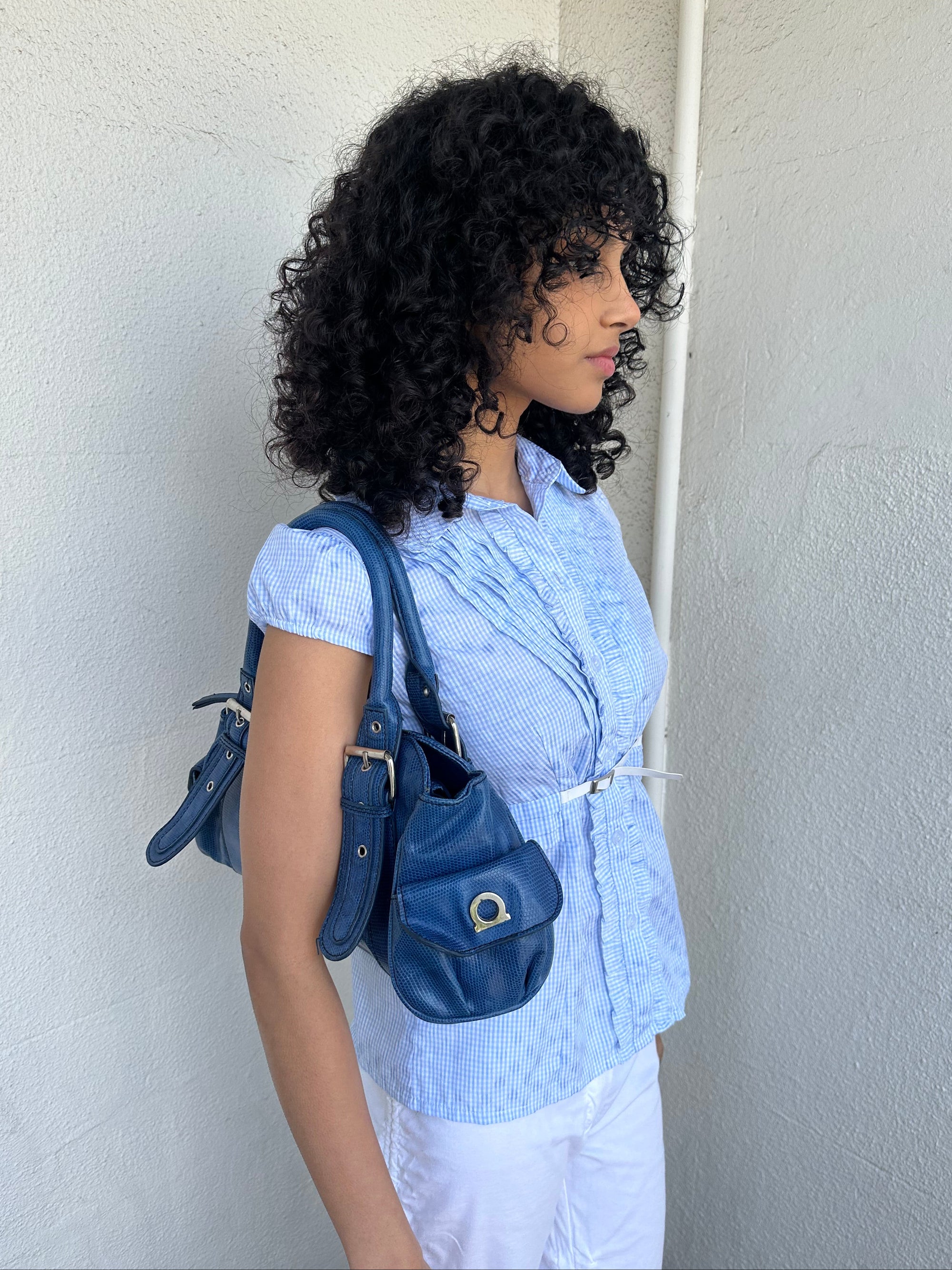 Woman wearing a Y2K 90s Royal blue faux leather shoulder bag with silver hardware and a sleek, structured shape. 