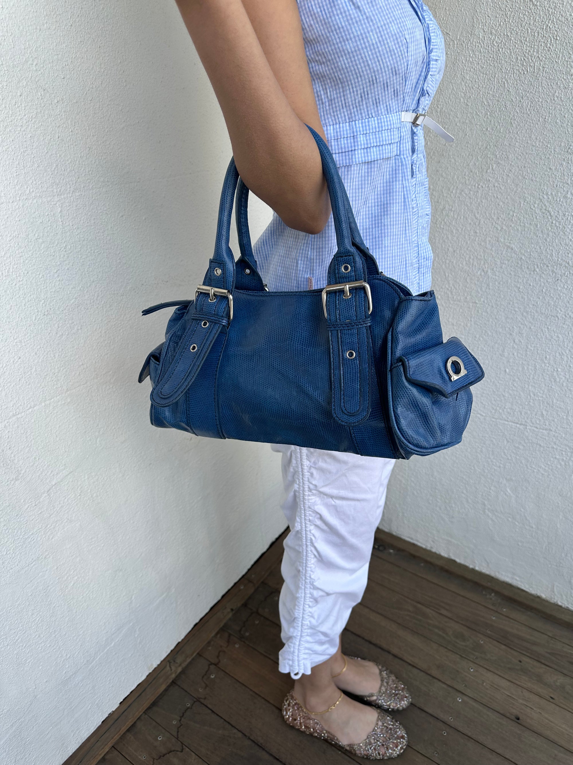 Woman wearing a Y2K 90s Royal blue faux leather shoulder bag with silver hardware and a sleek, structured shape. 