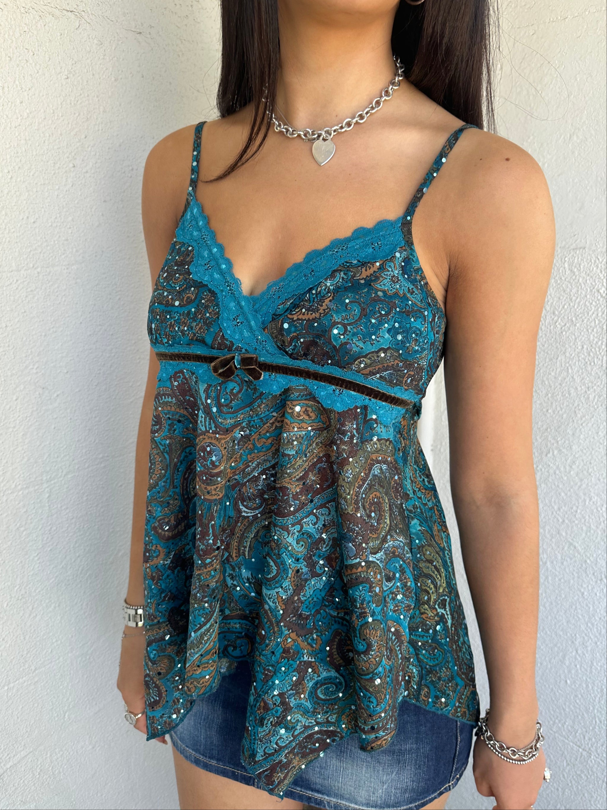 Woman Dressed in Y2K 00s Teal and brown sparkle paisley boho top featuring shimmer pieces all over for a subtle fairy-like glow.
