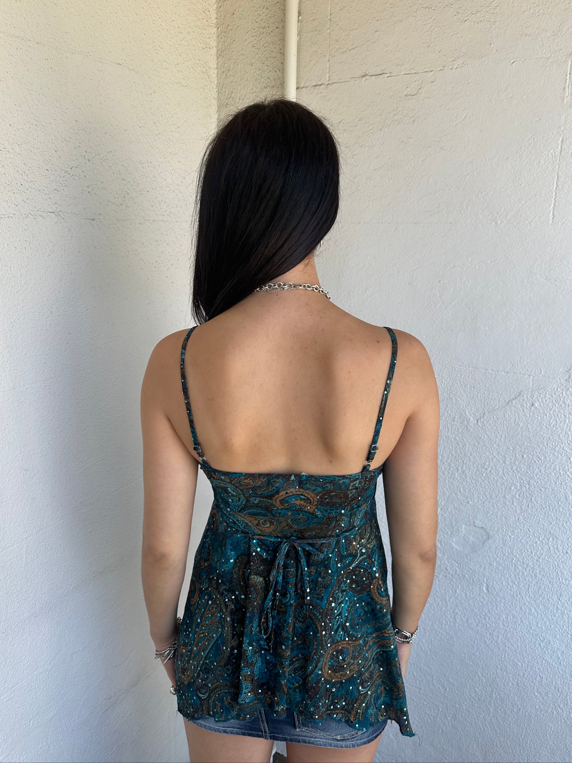 Woman Dressed in Y2K 00s Teal and brown sparkle paisley boho top featuring shimmer pieces all over for a subtle fairy-like glow.