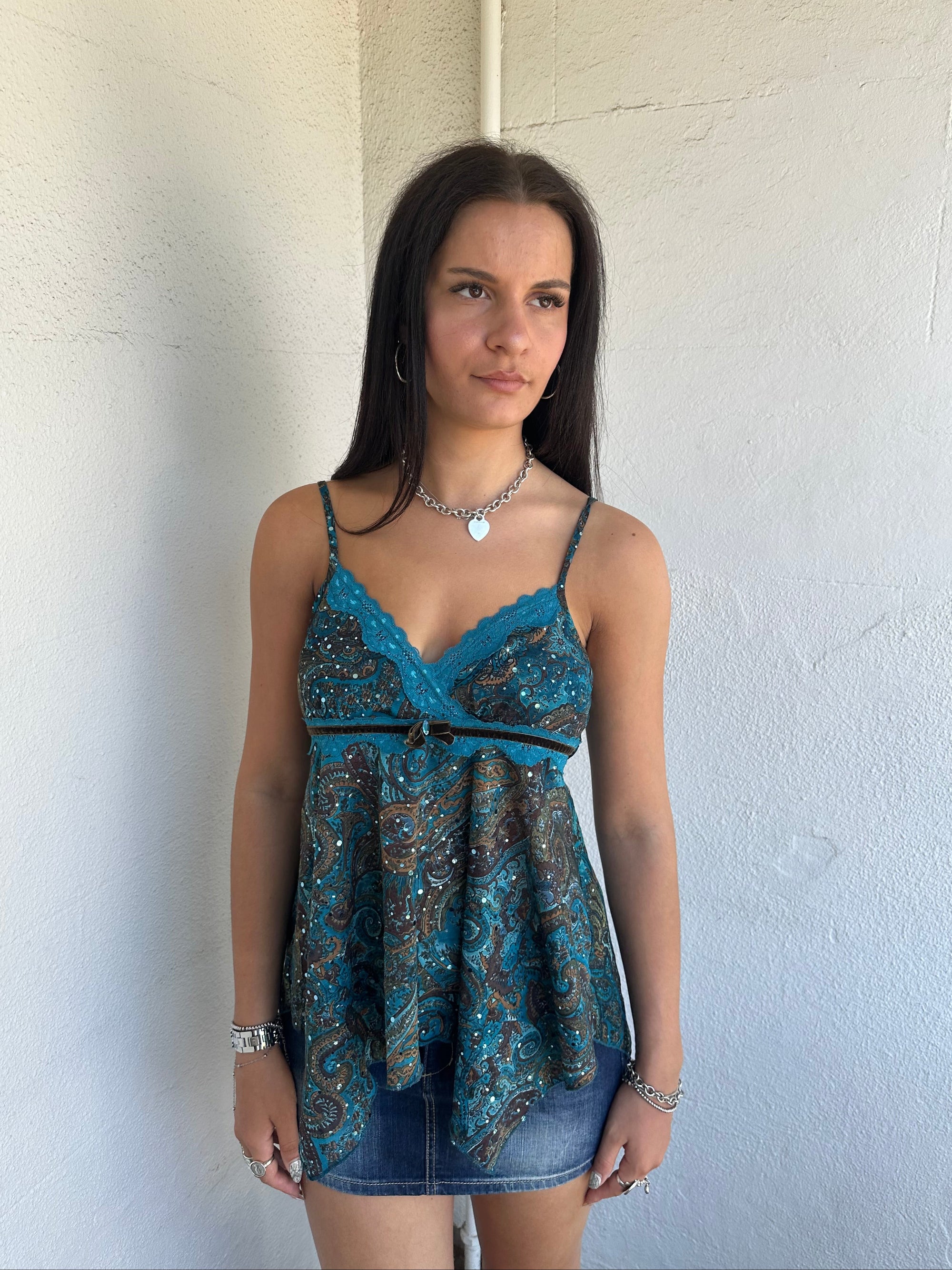 Woman Dressed in Y2K 00s Teal and brown sparkle paisley boho top featuring shimmer pieces all over for a subtle fairy-like glow.