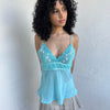 Women wearing a 00s Y2K Turquoise embroidered fairy cami with a lace bust featuring white and gold floral embroidery. 