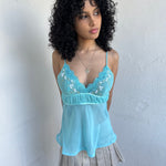 Women wearing a 00s Y2K Turquoise embroidered fairy cami with a lace bust featuring white and gold floral embroidery. 