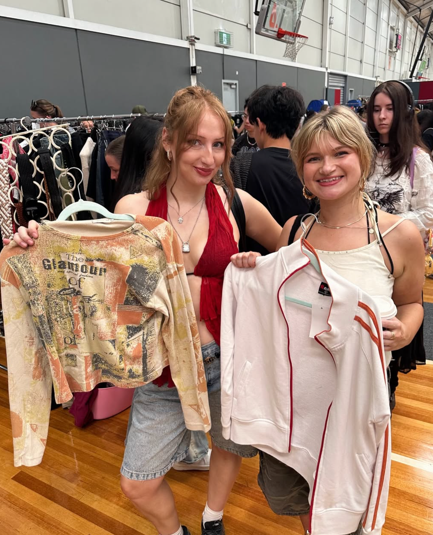 Two women holding up clothing items in a store setting