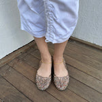Woman wearing a Y2K 90s Vivienne Westwood X Anglomania jelly ballet flats in a netted clear glitter style.