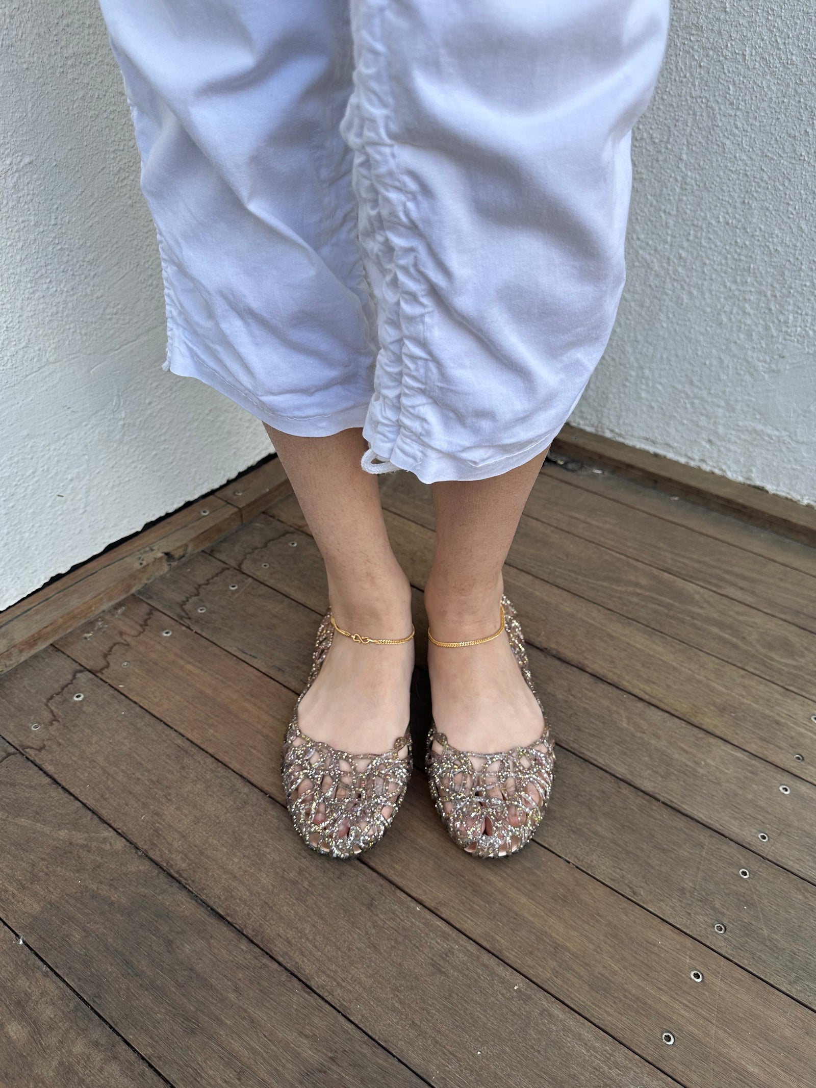 Woman wearing a Y2K 90s Vivienne Westwood X Anglomania jelly ballet flats in a netted clear glitter style.