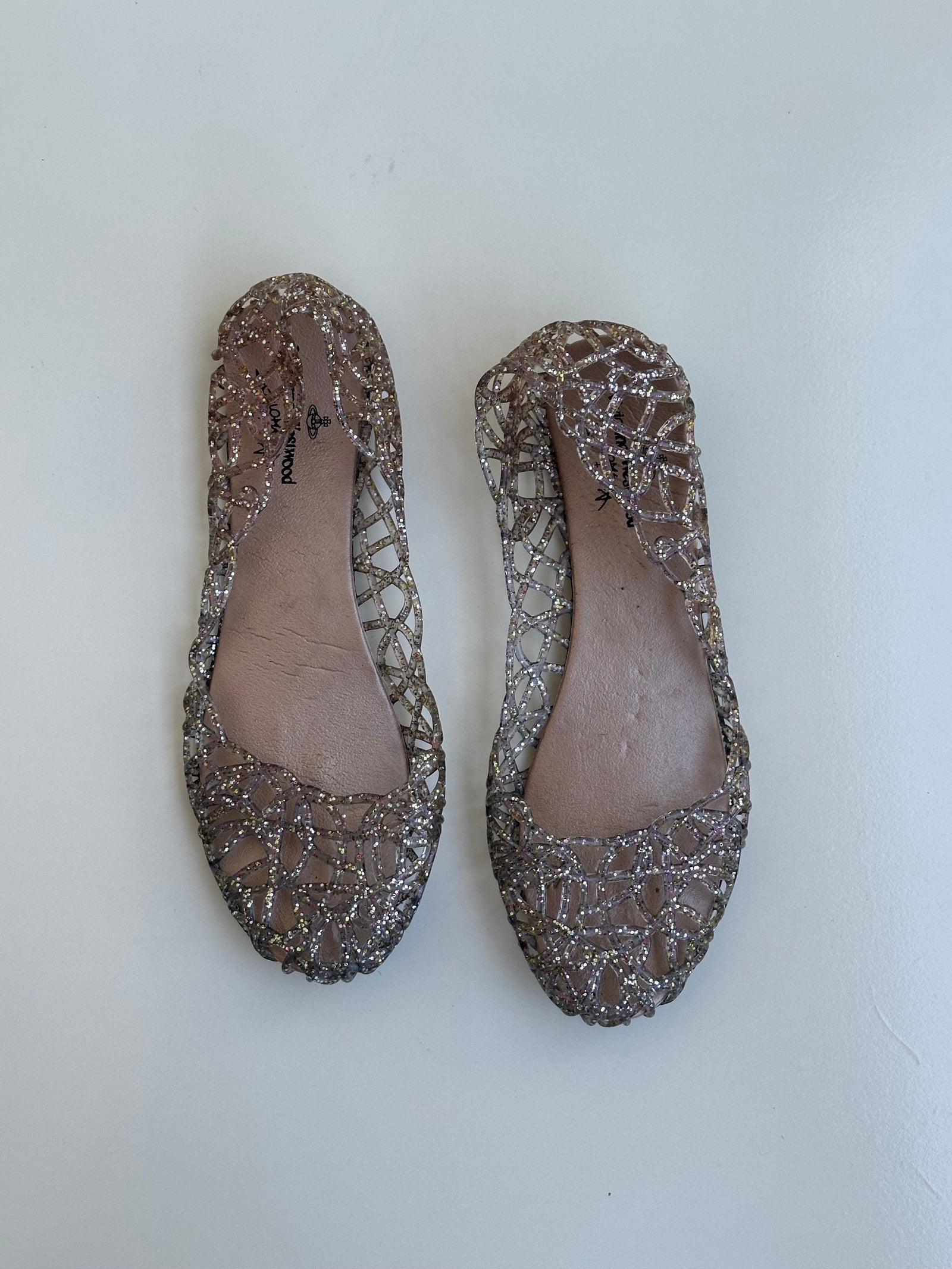 Woman wearing a Y2K 90s Vivienne Westwood X Anglomania jelly ballet flats in a netted clear glitter style.