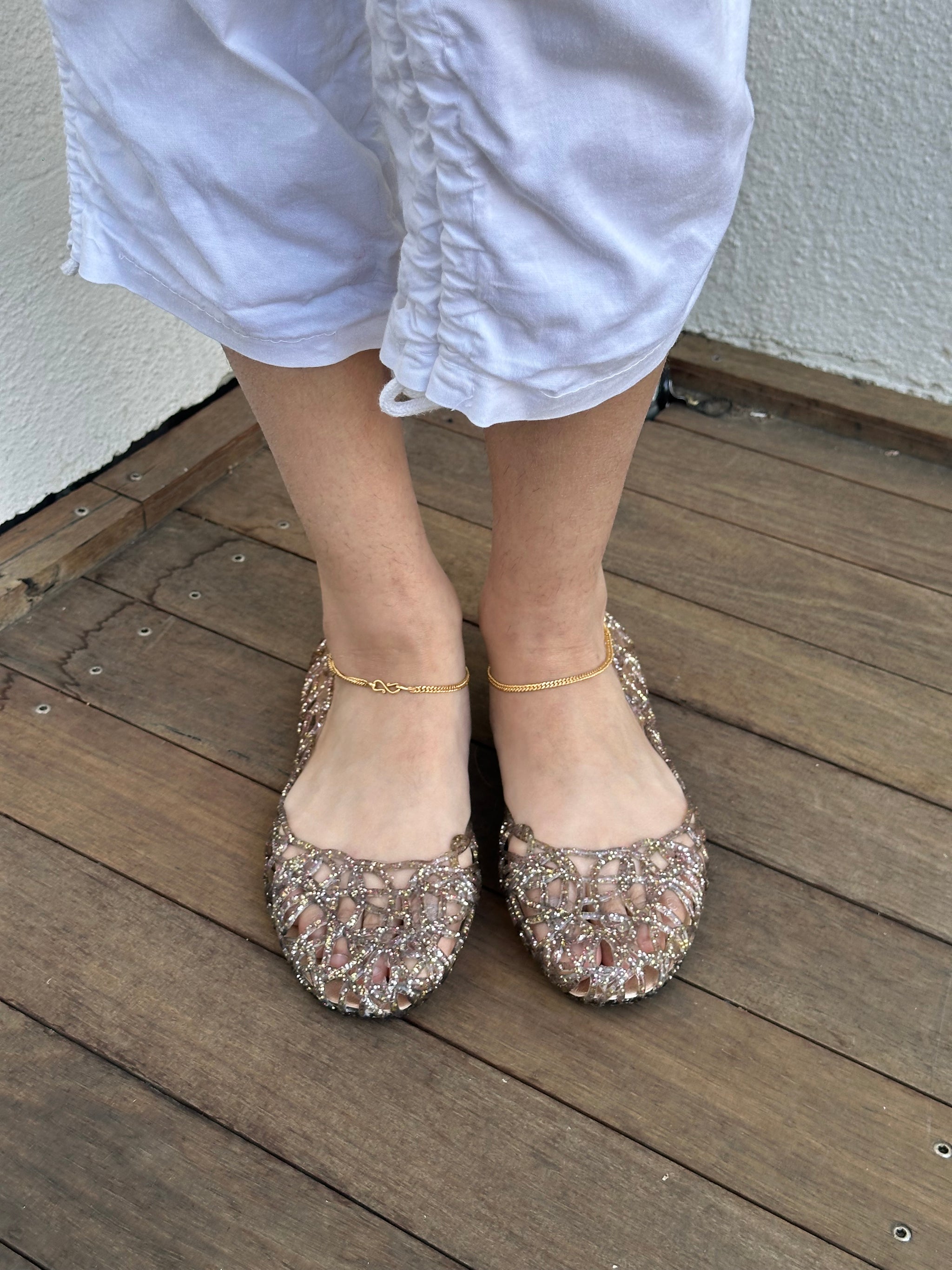 Woman wearing a Y2K 90s Vivienne Westwood X Anglomania jelly ballet flats in a netted clear glitter style.