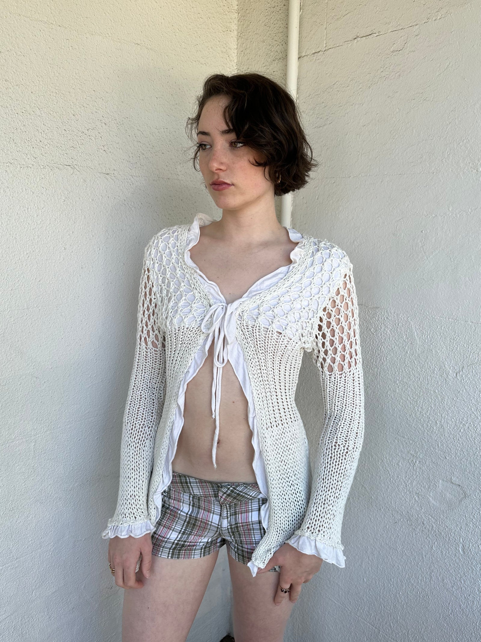 Woman Dressed in Y2K White crochet tie front cardigan featuring a layered bust design
