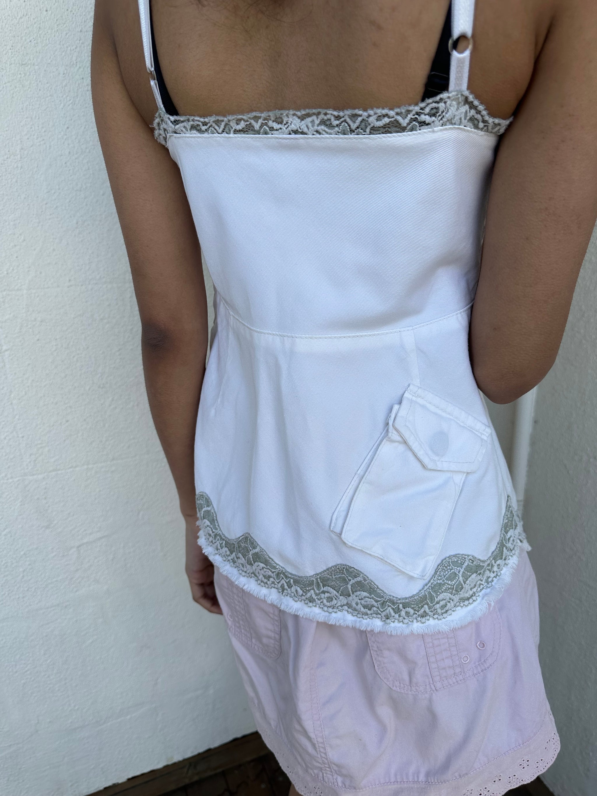 Woman wearing a Y2K 90s White denim fitted cami top with grey lace trim and a small patch pocket on the back sized for a flip phone! 