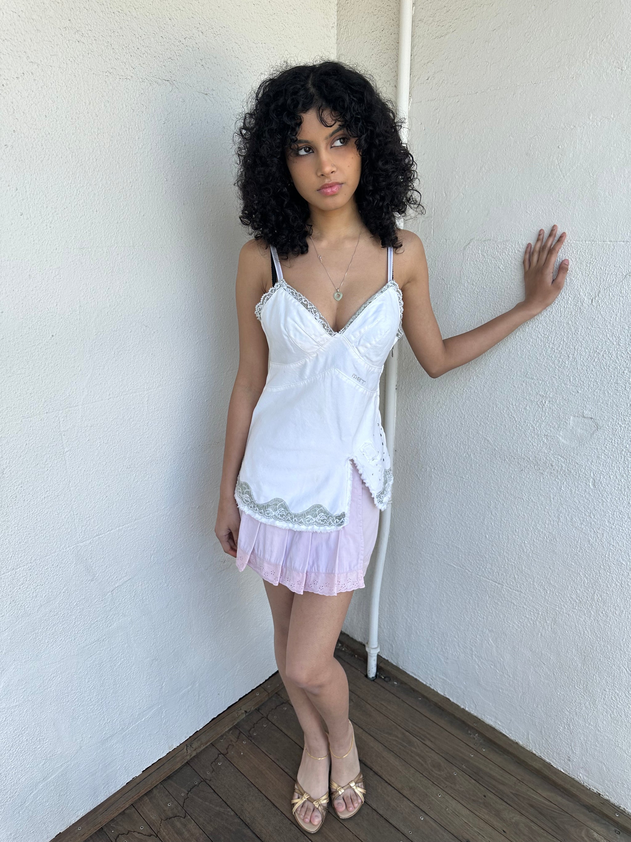 Woman wearing a Y2K 90s White denim fitted cami top with grey lace trim and a small patch pocket on the back sized for a flip phone! 