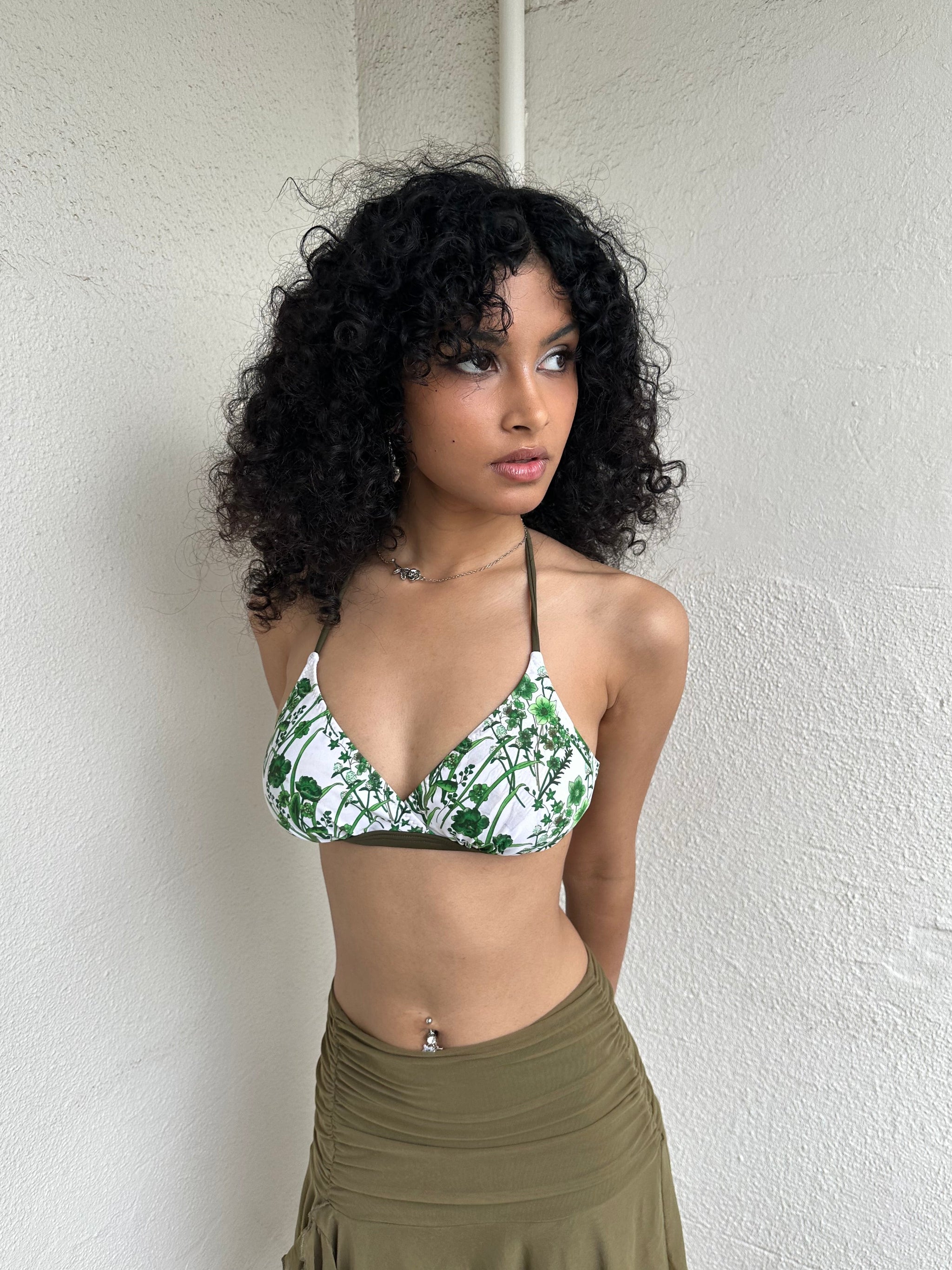 Woman Dressed in Y2K 00s White and green floral bikini top with a white base and green and khaki floral print throughout.