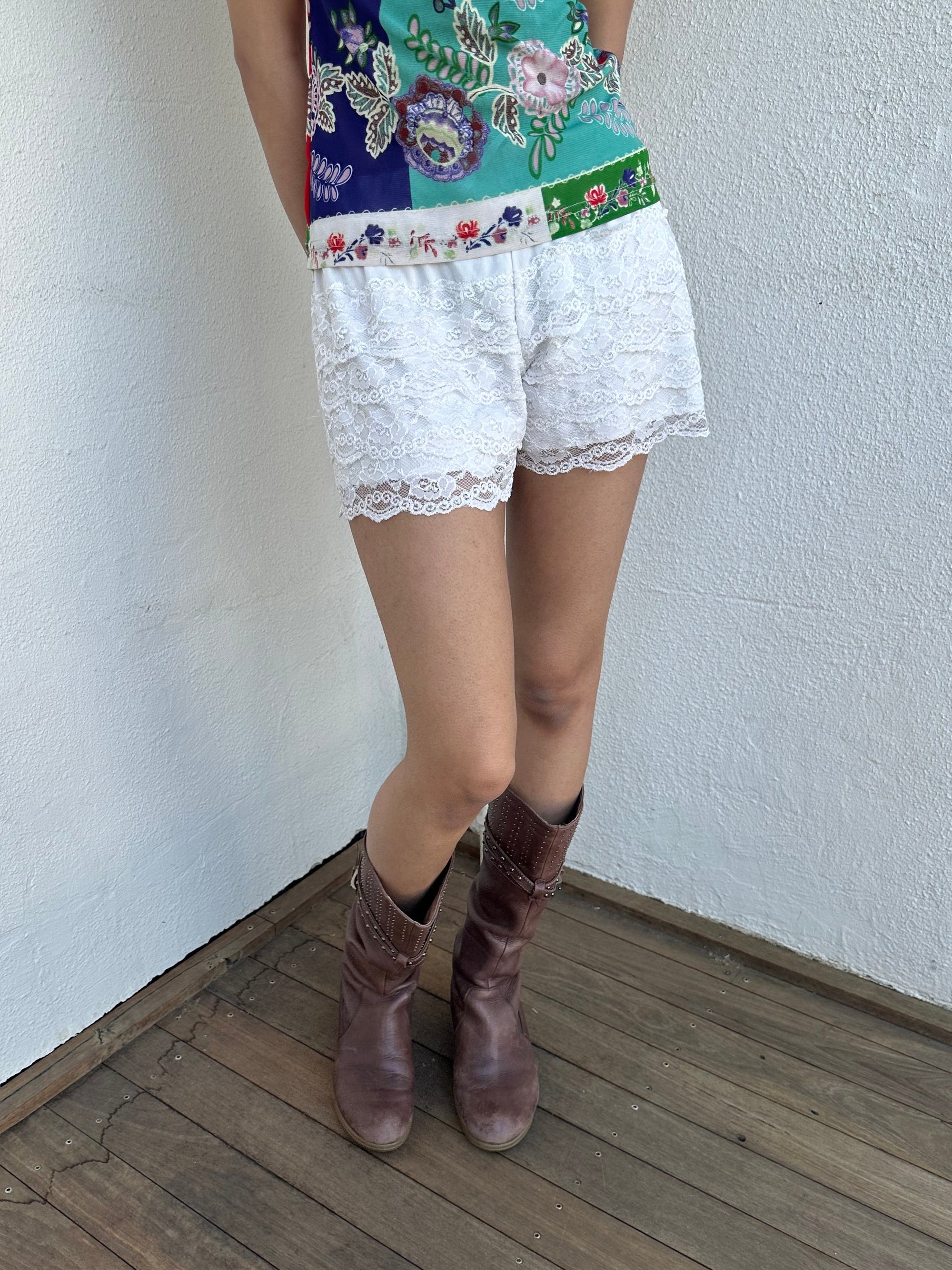 Woman wearing a Y2K 00s White lace bloomer shorts a festival classic. Delicate layered lace detailing with bow detail. 