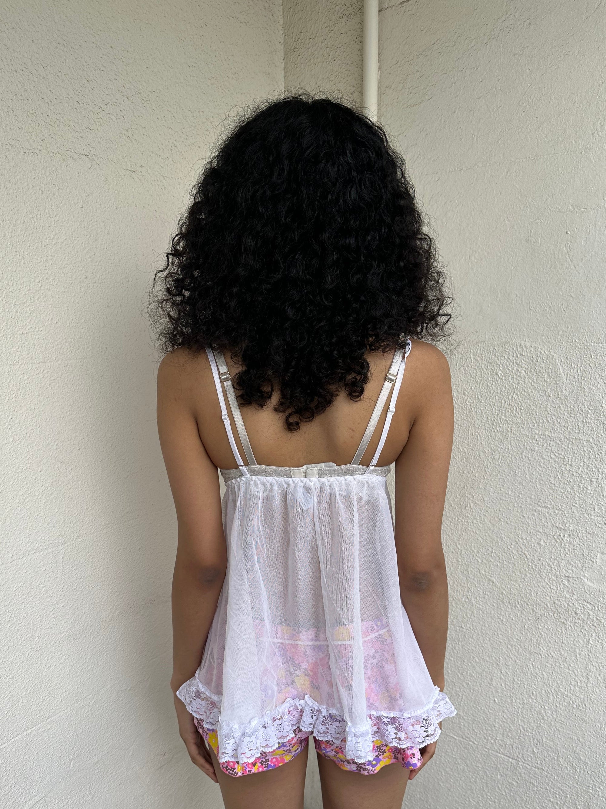 Woman Dressed in Y2K 00s White lace cami with a babydoll silhouette and fully sheer finish. 