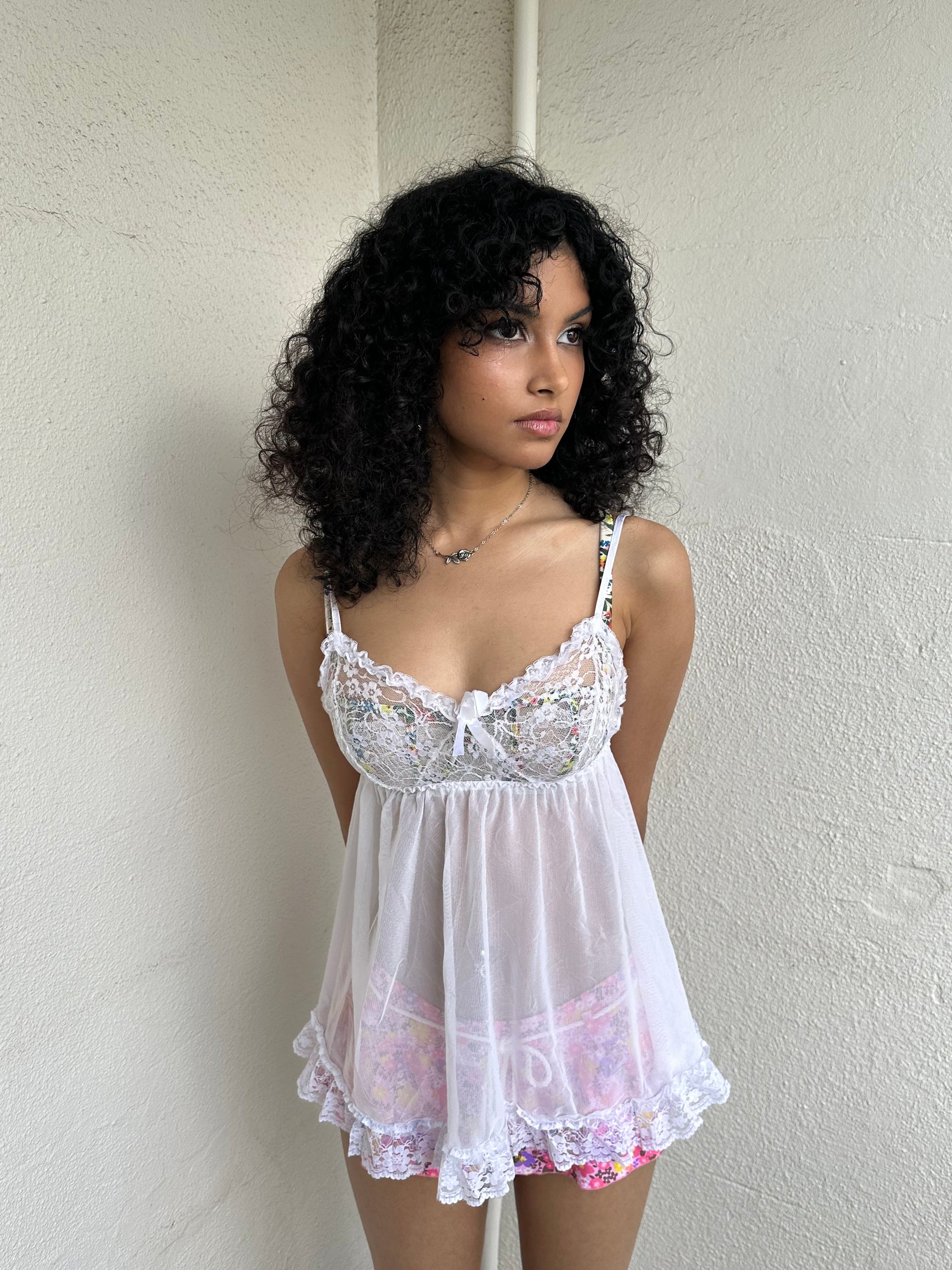 Woman Dressed in Y2K 00s White lace cami with a babydoll silhouette and fully sheer finish. 