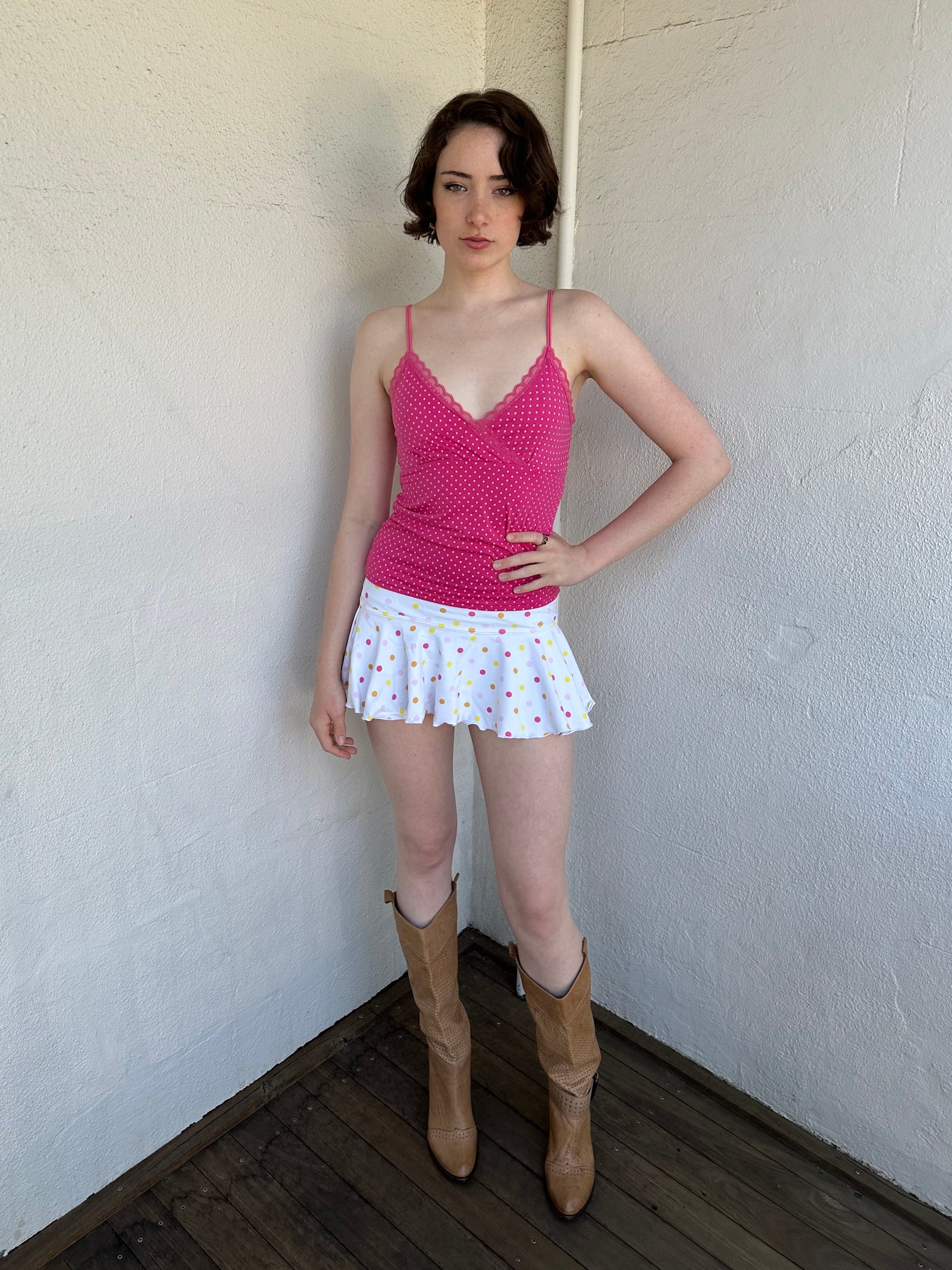 Woman Dressed in Y2K White and multicoloured polkadot mini skirt featuring a crisp white base with pink, yellow, and orange polkadots throughout.