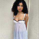 Woman Dressed in Y2K 00s White polkadot babydoll dress featuring a white base with classic polkadot detailing 