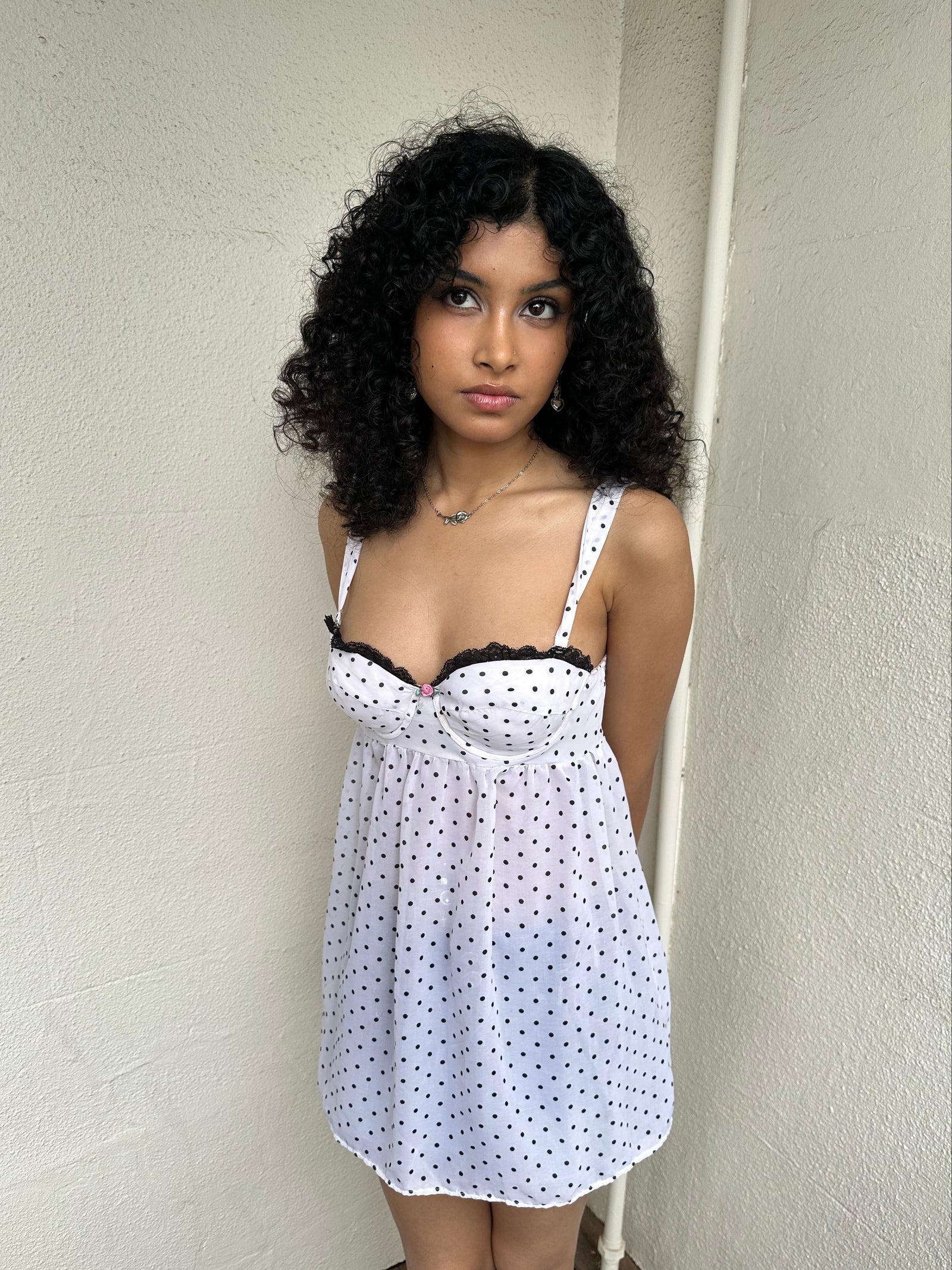 Woman Dressed in Y2K 00s White polkadot babydoll dress featuring a white base with classic polkadot detailing 