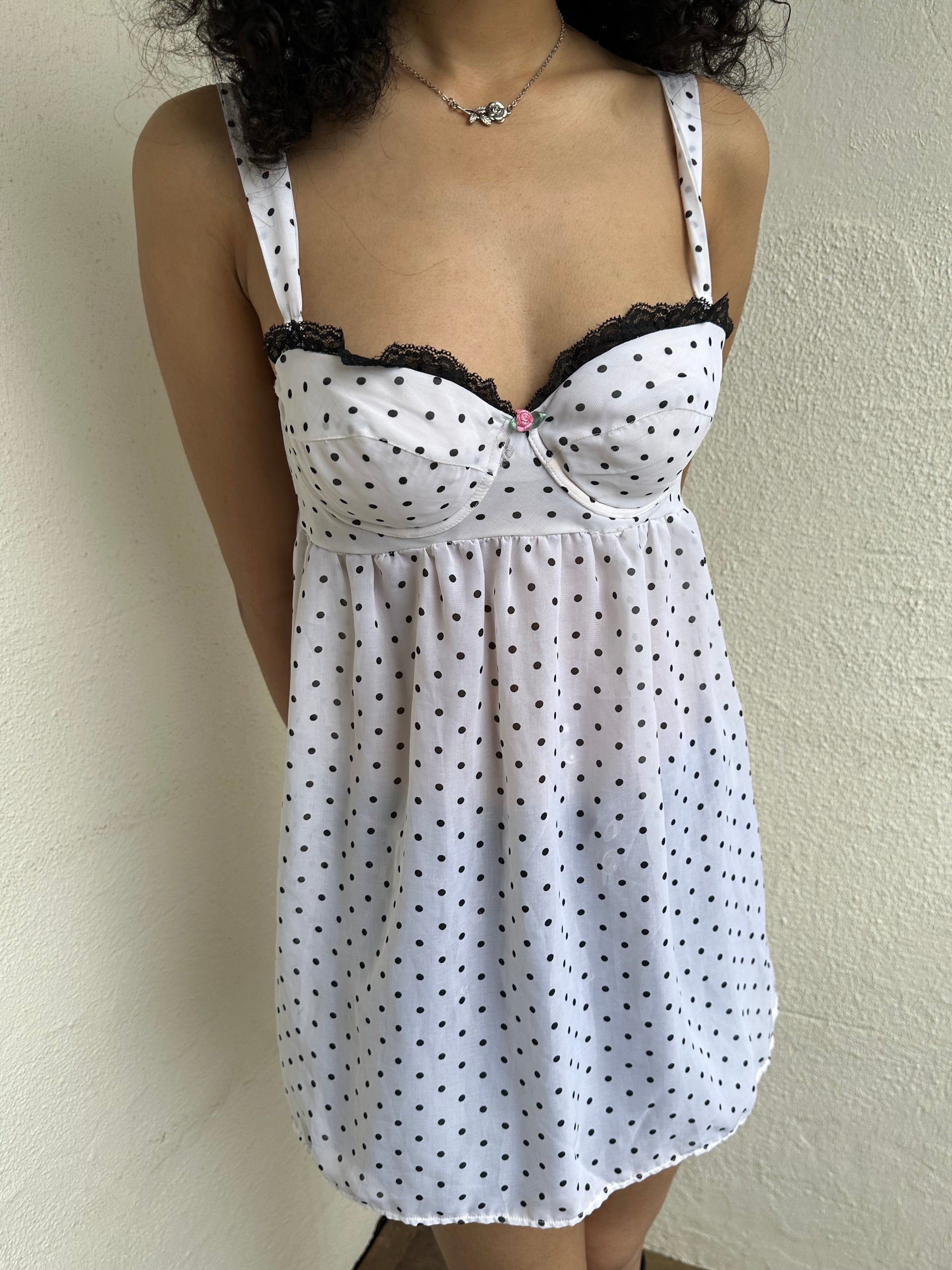 Woman Dressed in Y2K 00s White polkadot babydoll dress featuring a white base with classic polkadot detailing 