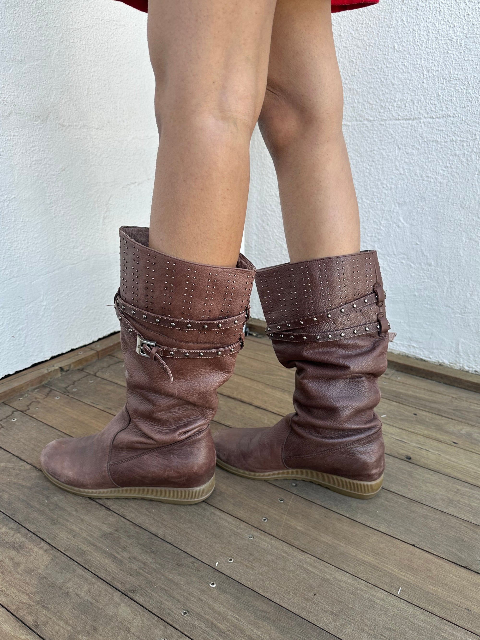 Woman wearing a Y2K 00s Y2K scrunched faux leather boots bring major Bratz energy with silver studded straps
