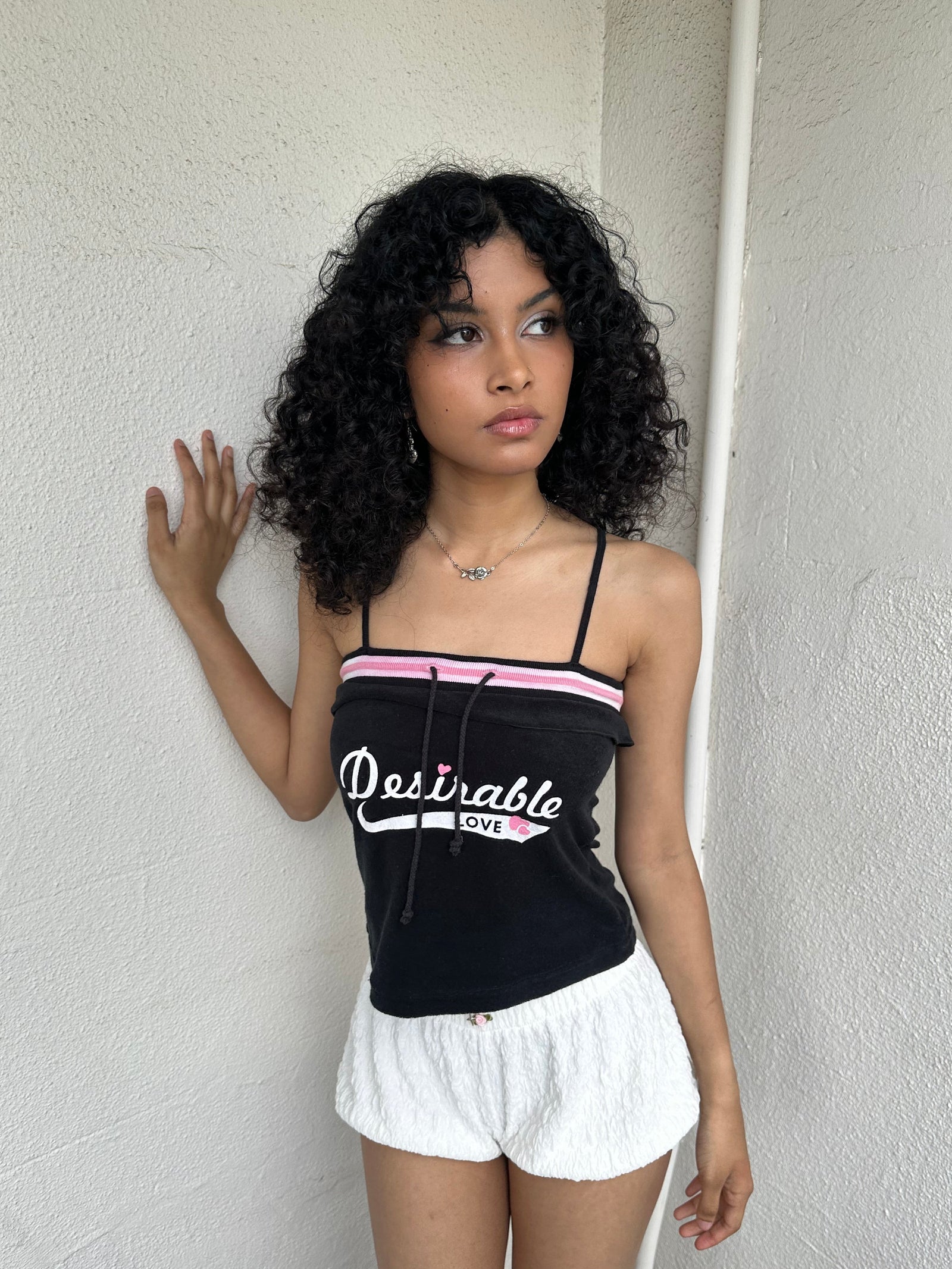 Woman Dressed in Y2K 00s Y2K sporty black graphic cami featuring pink and white “Desirable” printed across the front.