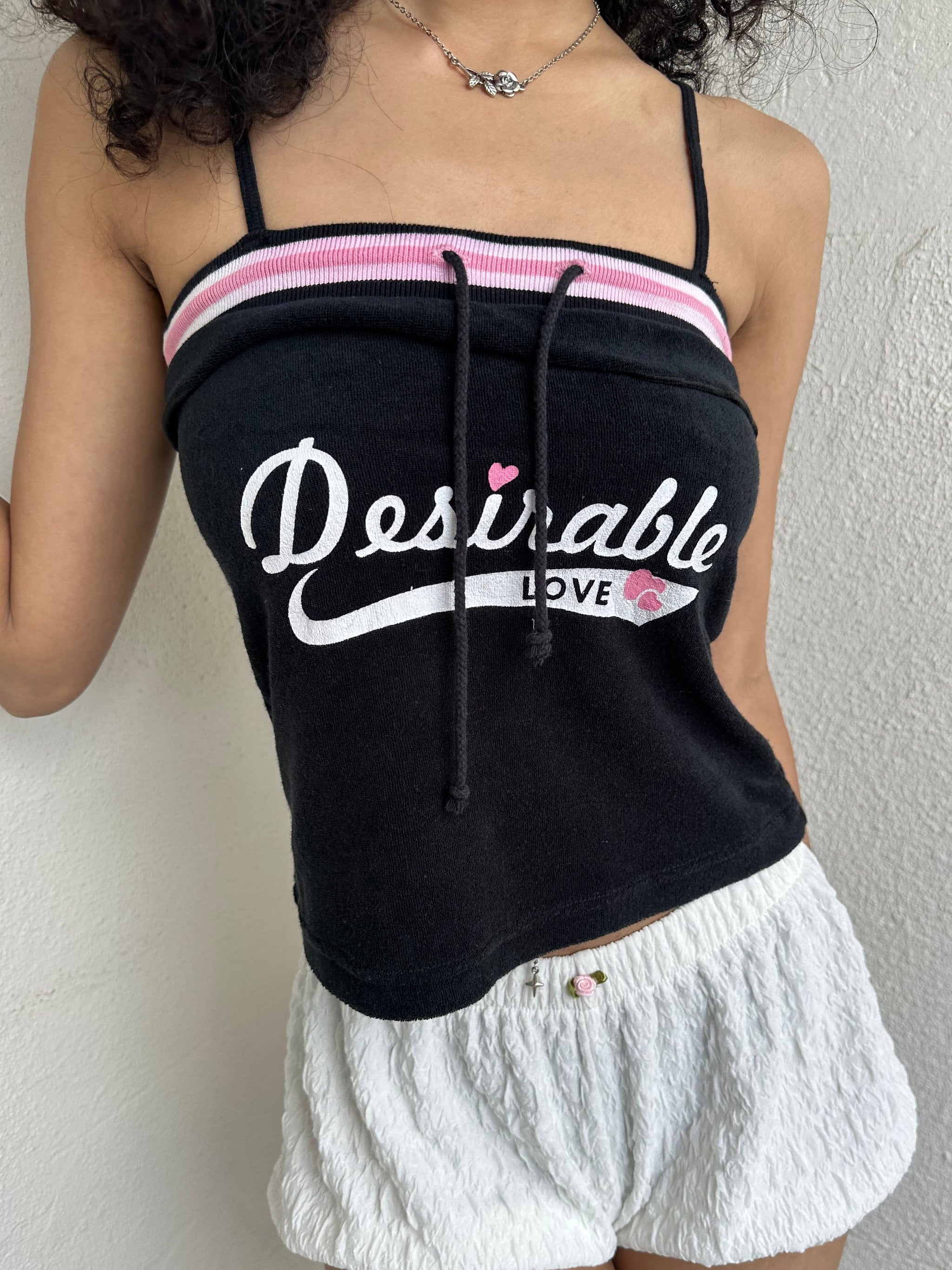 Woman Dressed in Y2K 00s Y2K sporty black graphic cami featuring pink and white “Desirable” printed across the front.