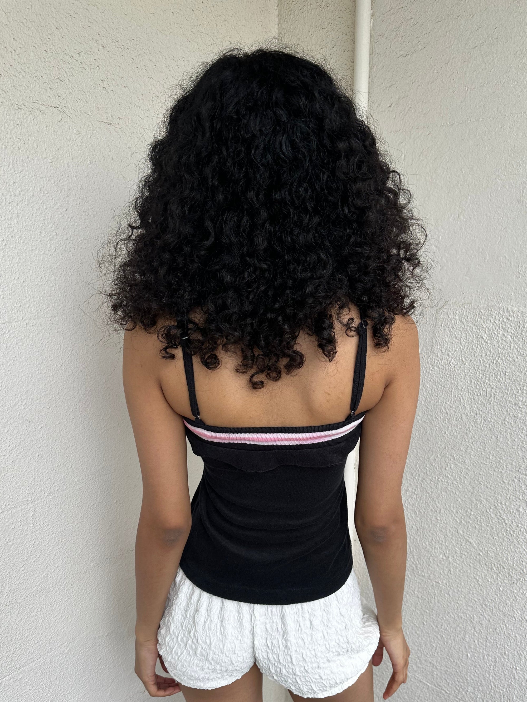 Woman Dressed in Y2K 00s Y2K sporty black graphic cami featuring pink and white “Desirable” printed across the front.