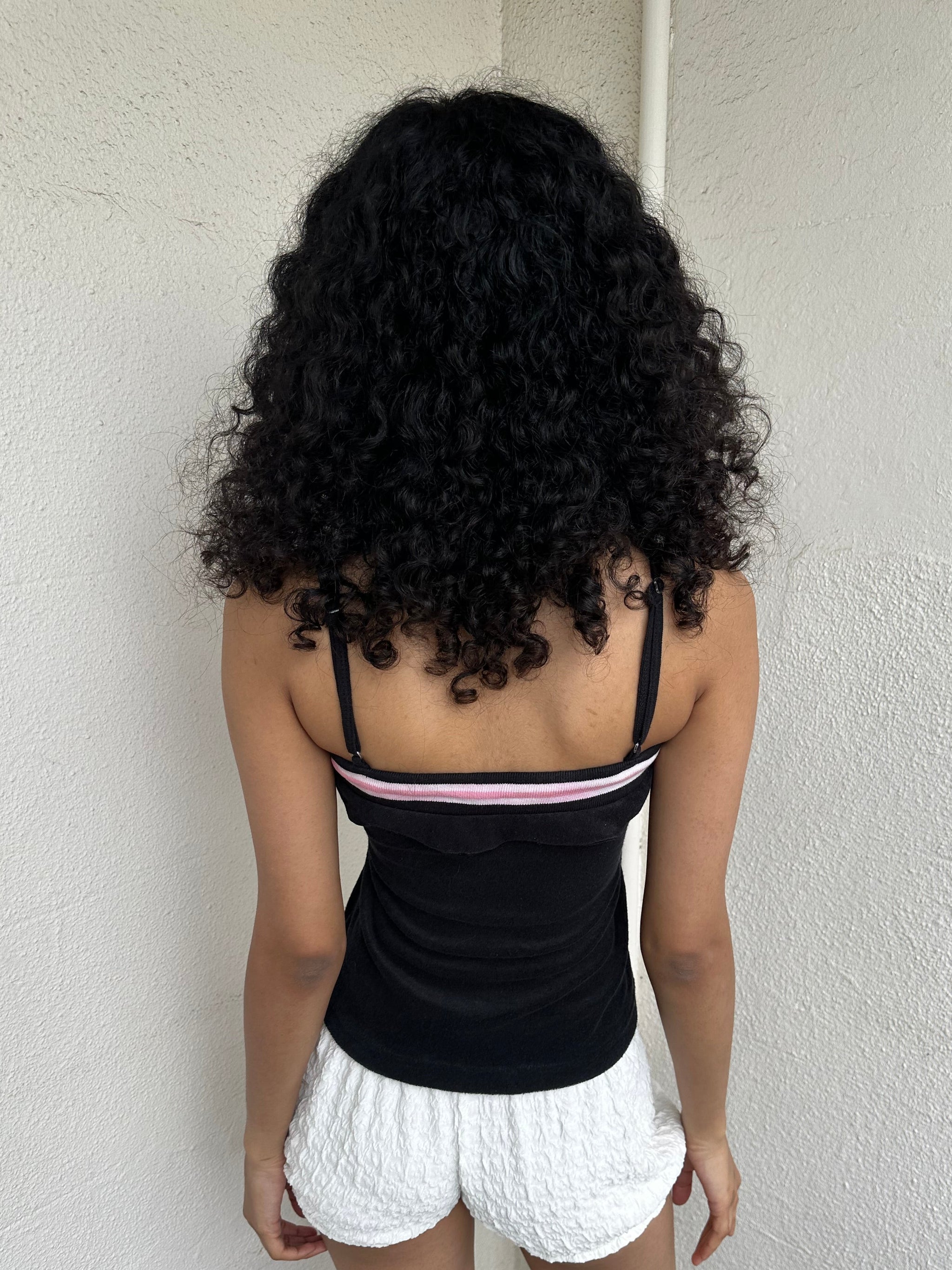 Woman Dressed in Y2K 00s Y2K sporty black graphic cami featuring pink and white “Desirable” printed across the front.