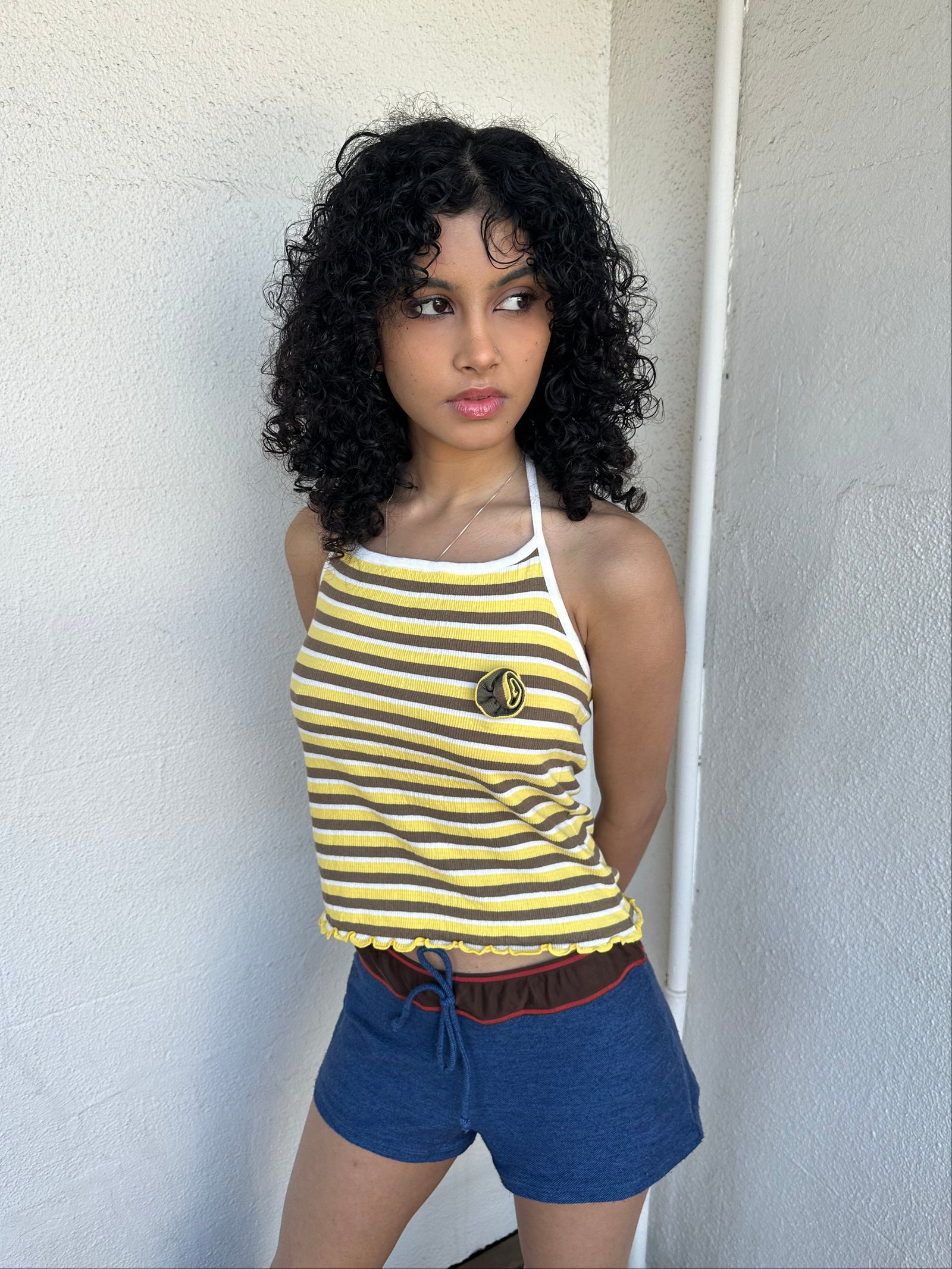 Women wearing a 00s Y2K Elle yellow, white and brown stripe halter top featuring a flower rosette detail on the front.