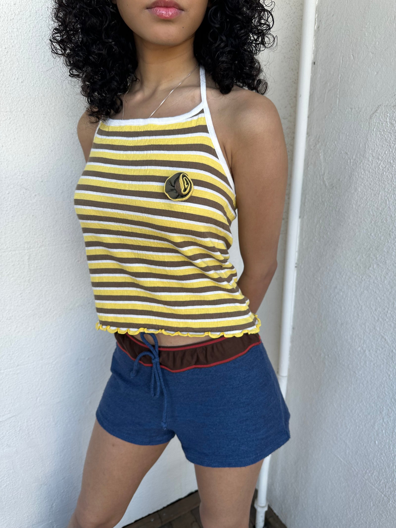 Women wearing a 00s Y2K Elle yellow, white and brown stripe halter top featuring a flower rosette detail on the front.